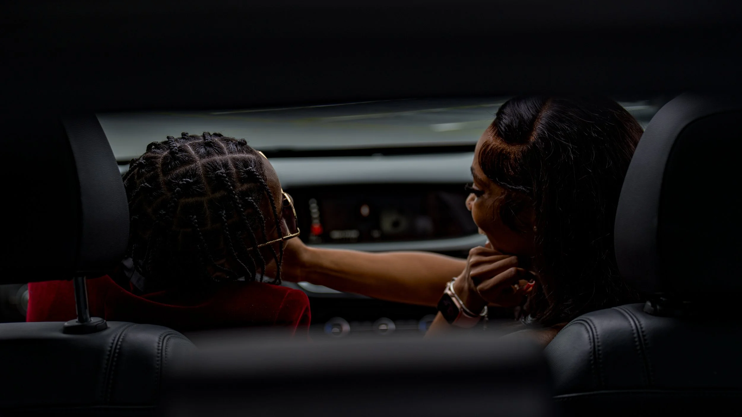 A woman smiling and touching a child's shoulder inside a car at night