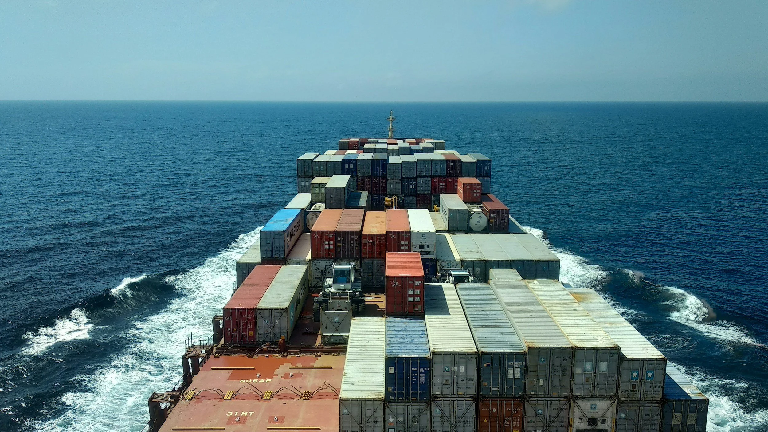 Cargo ship with stacked shipping containers sailing on the ocean.