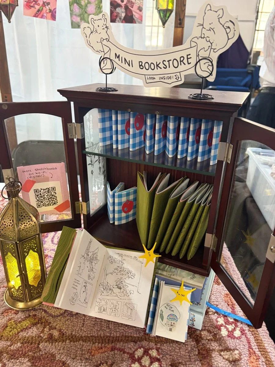 I set up a "Mini Bookstore" where I held my travel sketchbook copies and a small fruit sticker zine. I handbound these myself!
