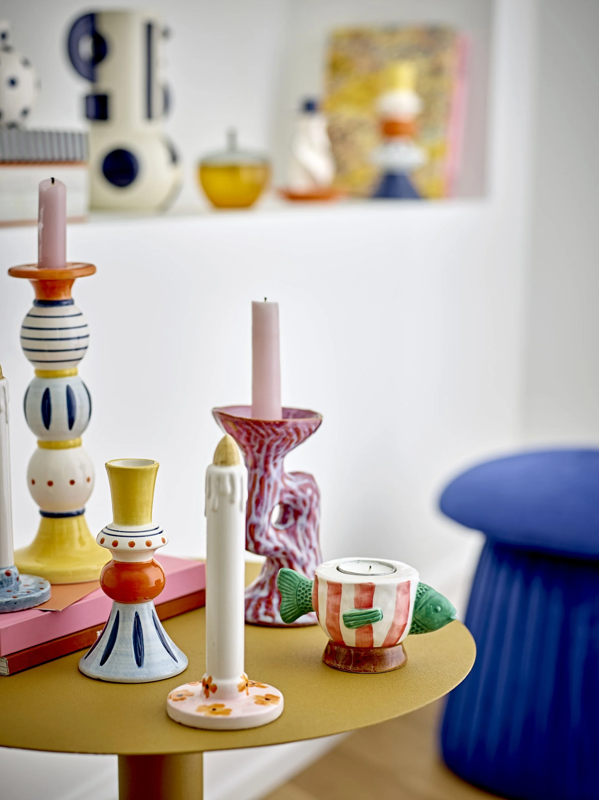 Velas decorativas y figuras de cerámica de la marca blomingville con forma de pez en una mesa en un ambiente colorido y moderno.