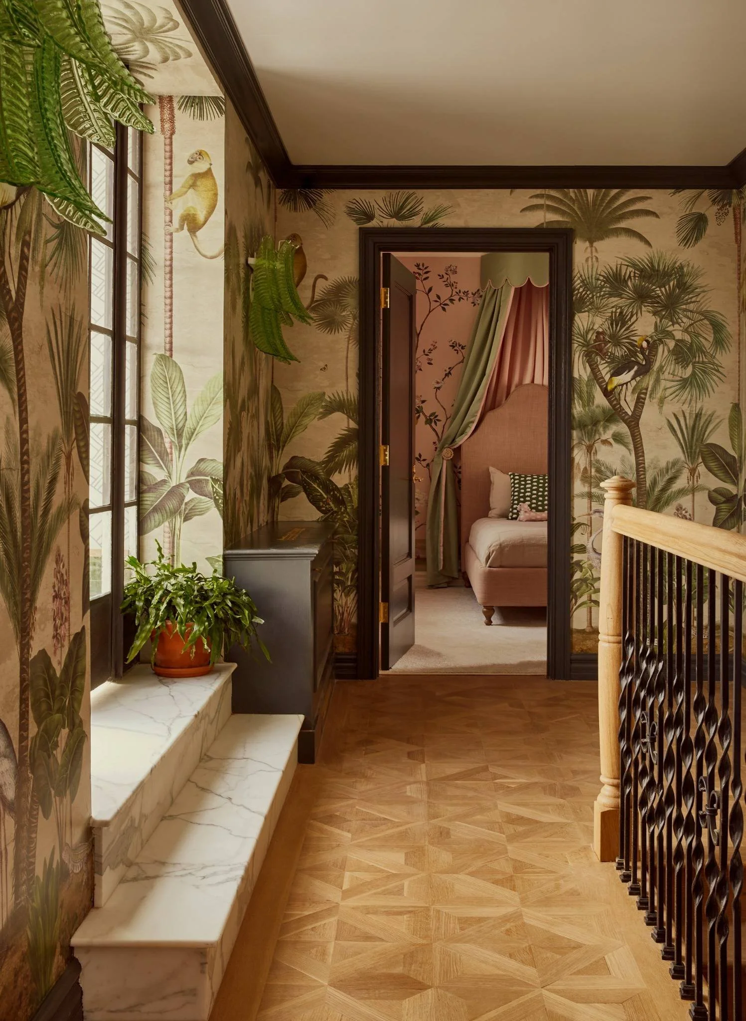 Interior view of a hallway with tropical-themed wallpaper, a window with a marble sill, a potted plant, and a view into a bedroom with a canopy bed.
