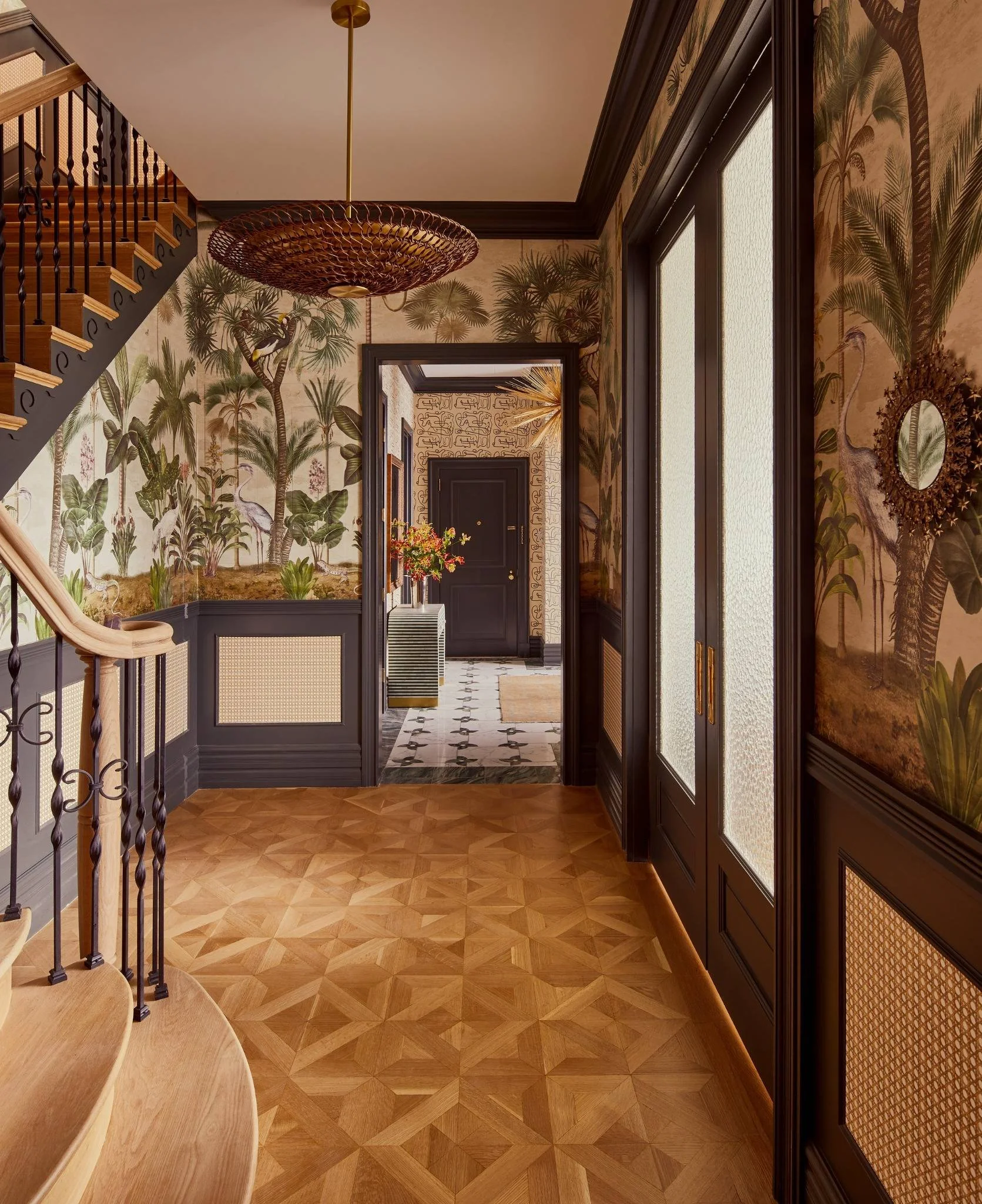 Interior hallway with tropical wallpaper, wooden floor, black doors, and decorative elements.