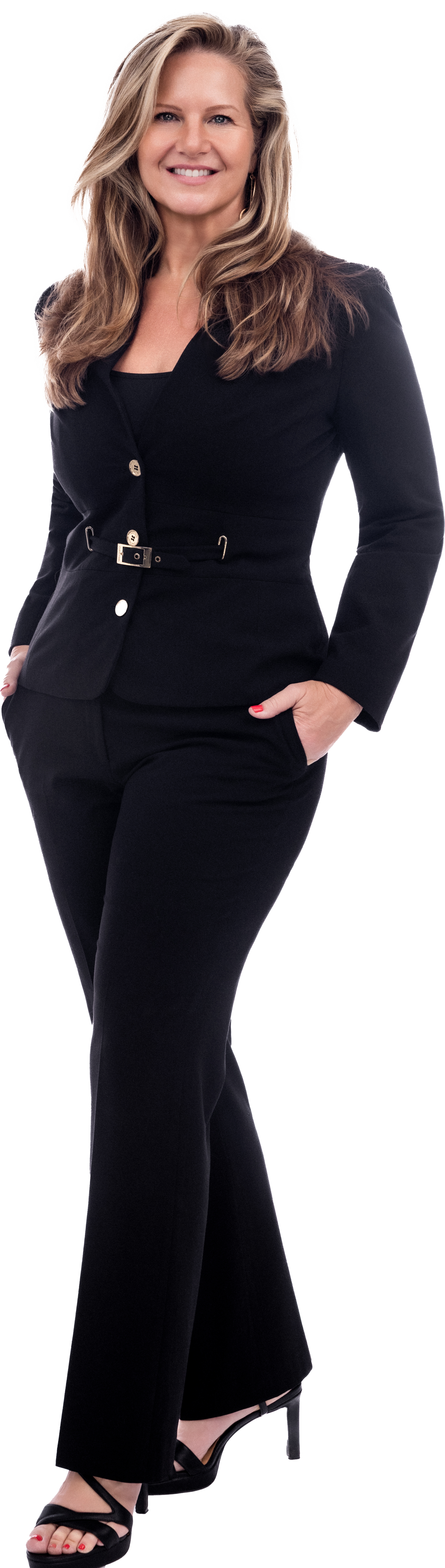 A woman with long, wavy blonde hair is standing confidently with her hand in her pocket. She is smiling and wearing a black suit with a fitted blazer and matching pants, paired with black high heels.