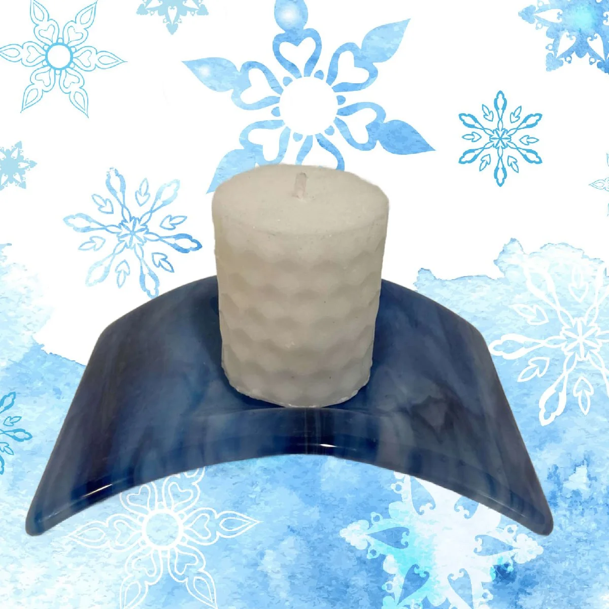 A white candle on a blue plate with a winter-themed background of snowflakes.