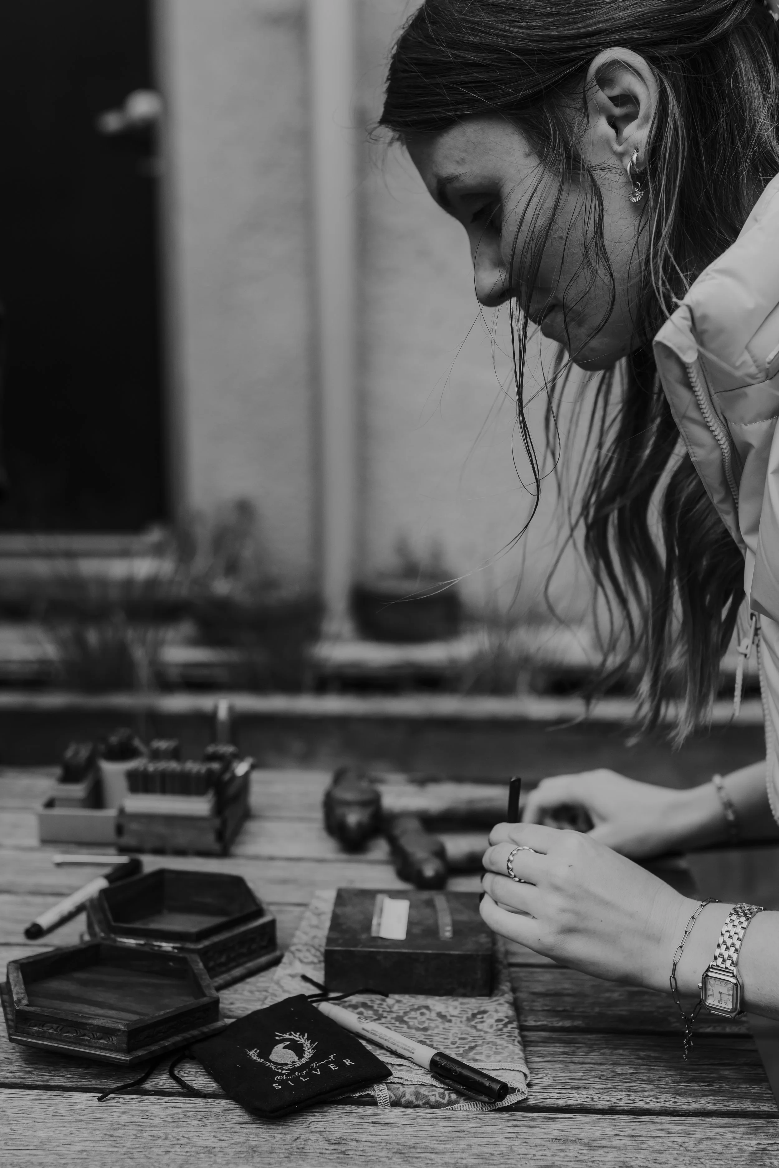 A woman with long hair is hand stamping her custom made wedding band for her Braidwood Elopement