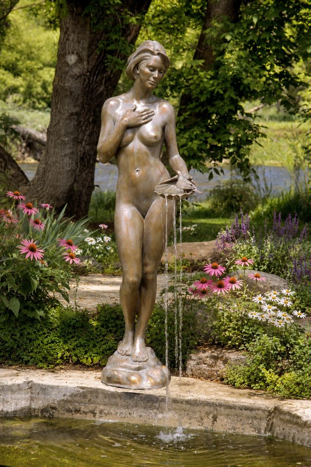 A romantic realist bronze fountain by Victor Issa titled "The Bird Bath" displayed at the edge of a reflecting pool