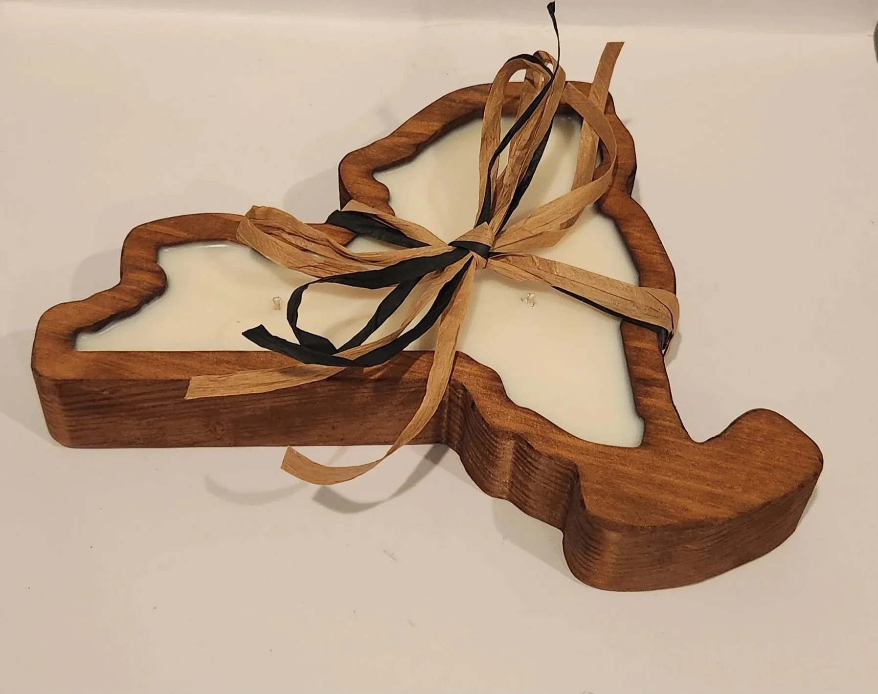 A wooden silhouette candle made in the shape of New York State with soy wax