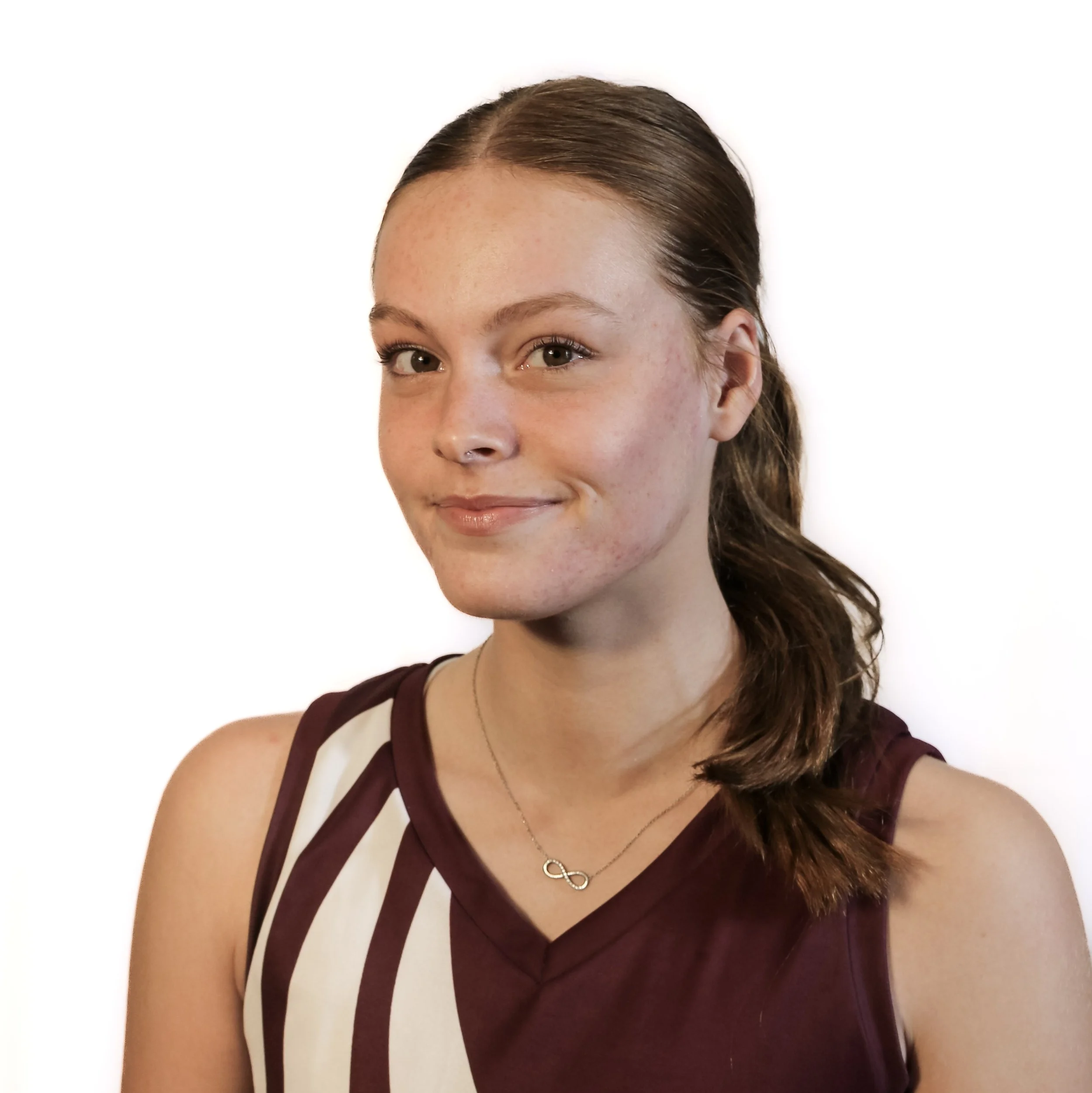 Close-up of a young woman with brown hair, blue eyes, light skin with freckles, wearing a maroon top and a silver infinity necklace, smiling slightly against a white background.