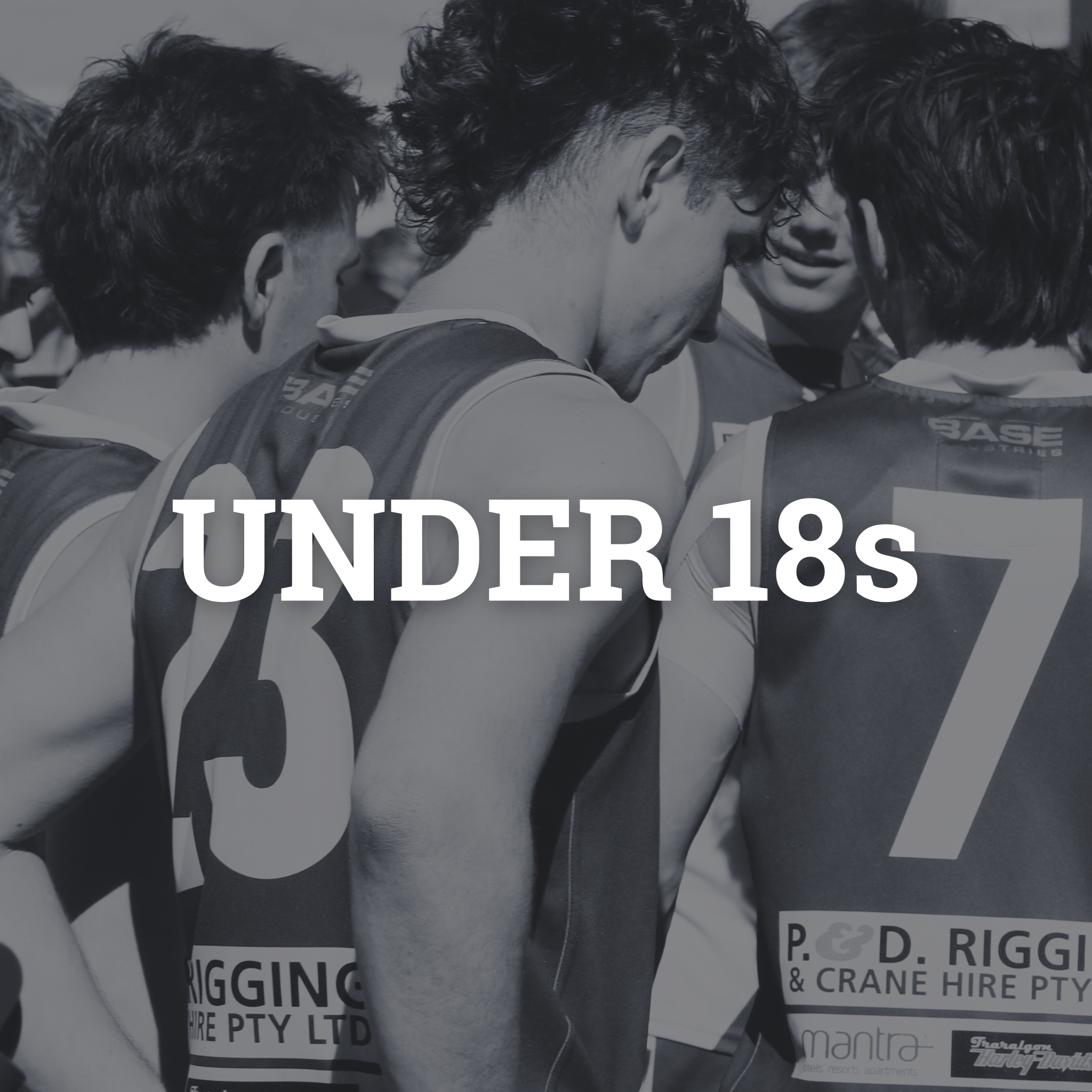 A group of young male athletes in sports uniforms huddle together during a game or practice, with the focus on their heads and shoulders.