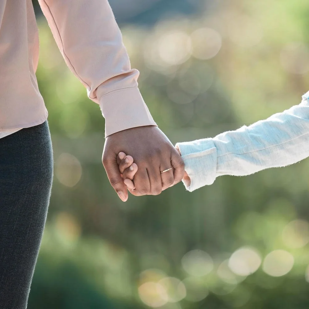 Close up on a little boy and his mother holding hands in nature
