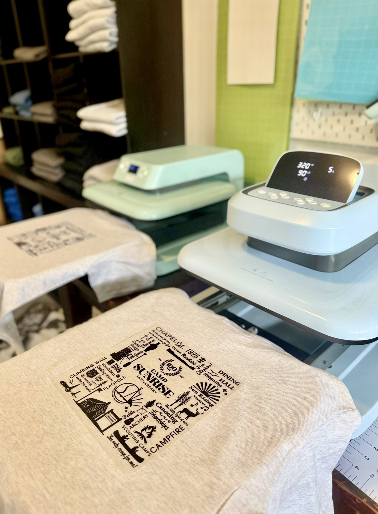 Close-up of a fabric with a black graphic design that includes various outdoor activities and landmarks, laid on a table with other sewing or crafting supplies nearby.