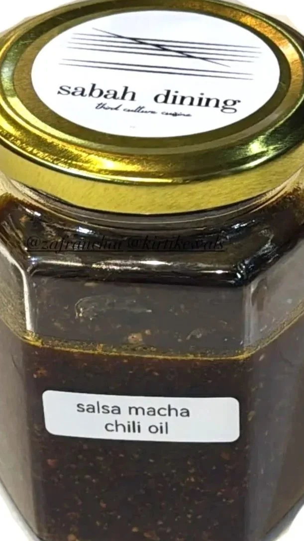A jar of salsa macha chili oil with a gold lid, labeled from Sabah Dining.