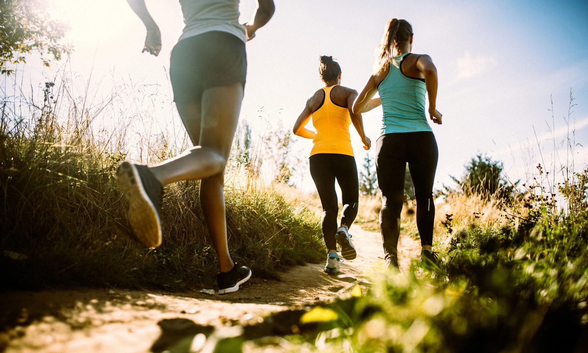 Three women jogging on a trail.