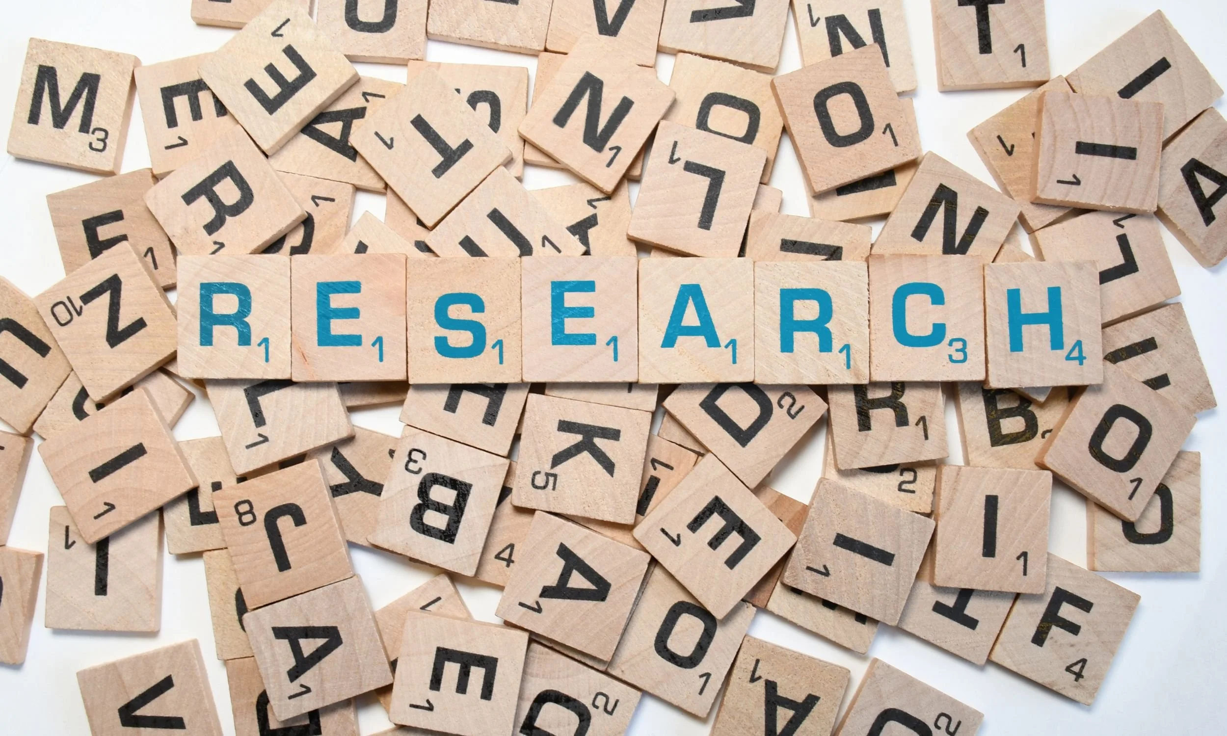 Scrabble tiles with blue letters spelling 'Research.