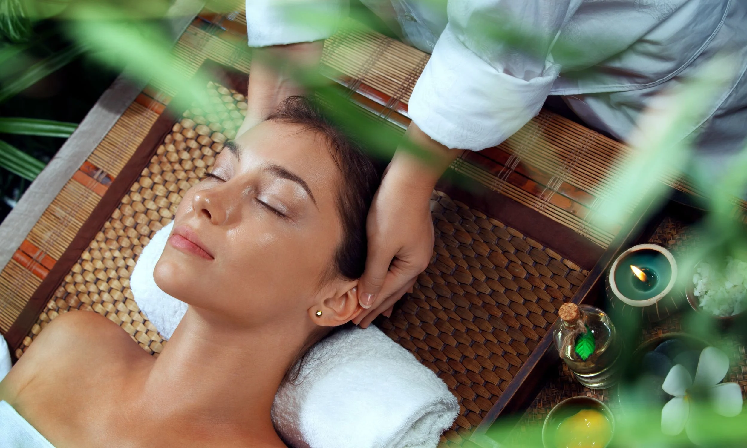 A woman lying down and getting a head massage.