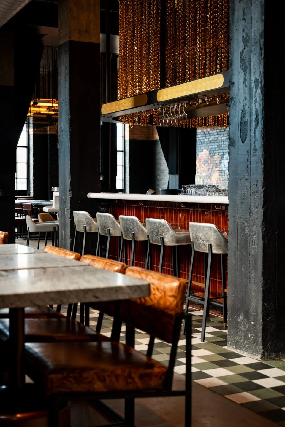 Interior of a stylish bar with barstools, a marble table, and a decorative gold chandelier.