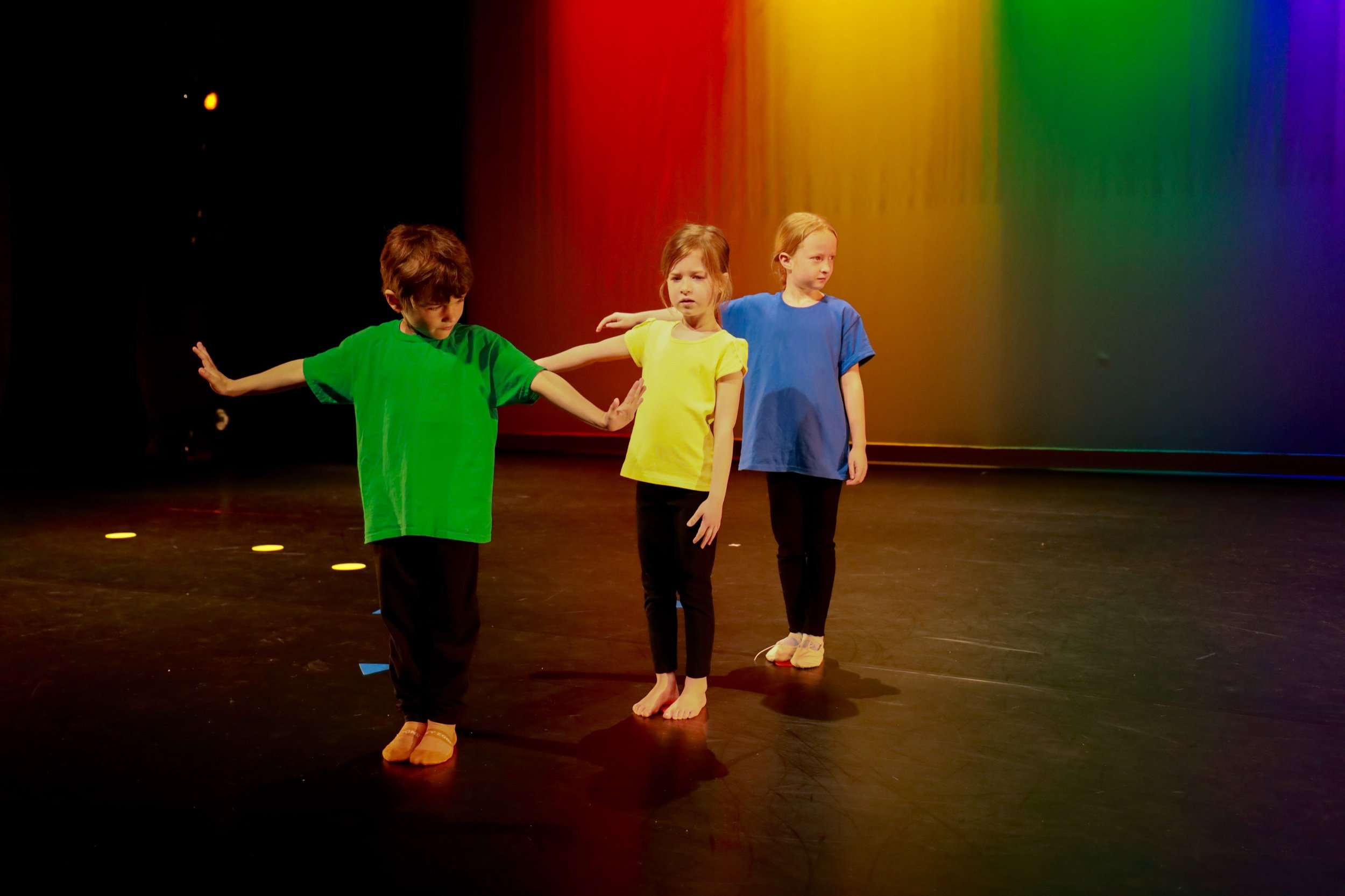 Three young dancers on stage right arm reaching side