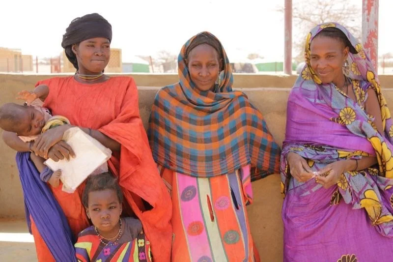 Three women and two children in colorful attire.
