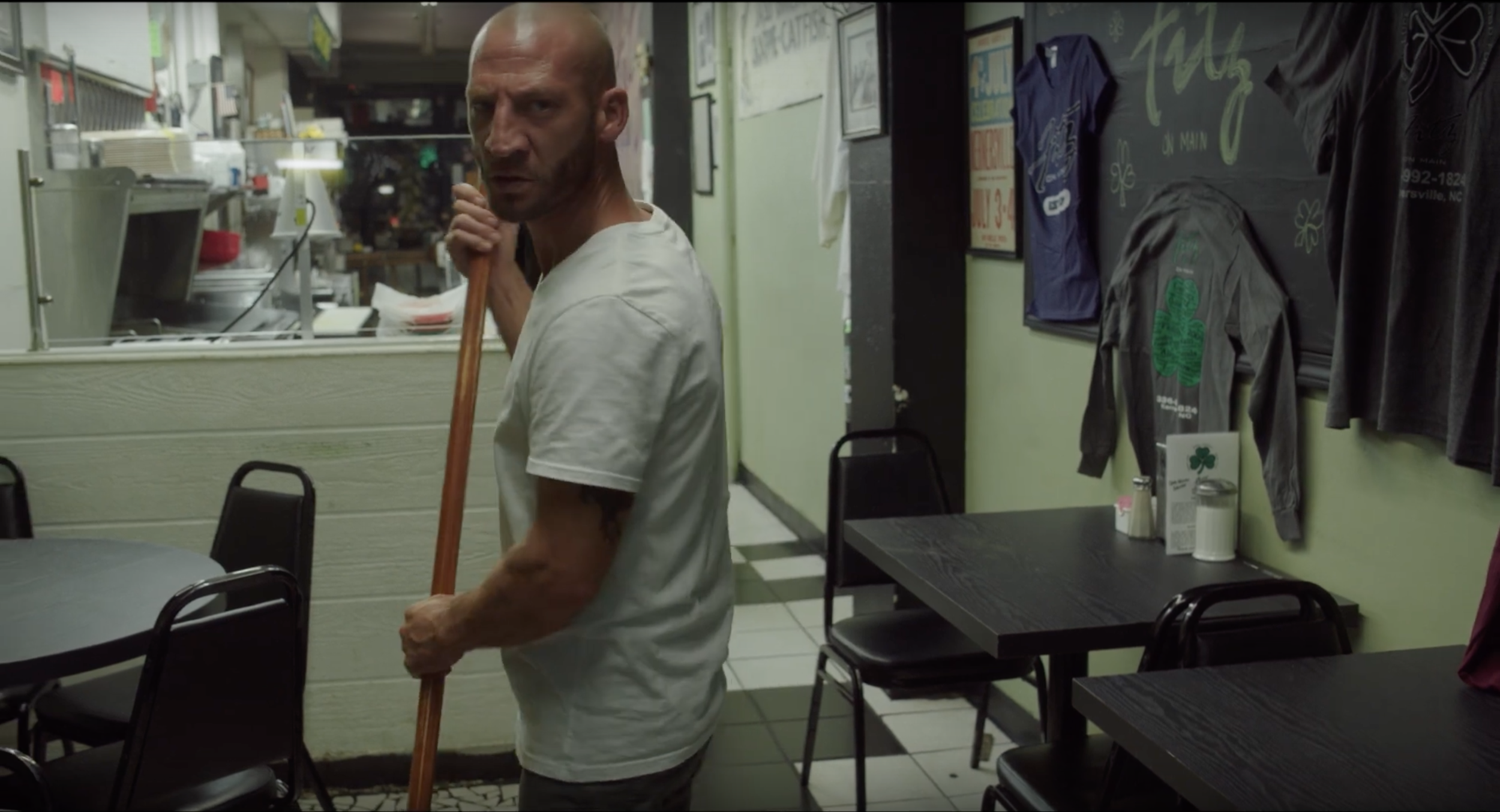 Man leaning on a broom in a diner.