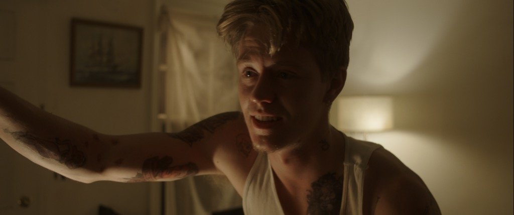 Man with tattoos in a dimly lit room.