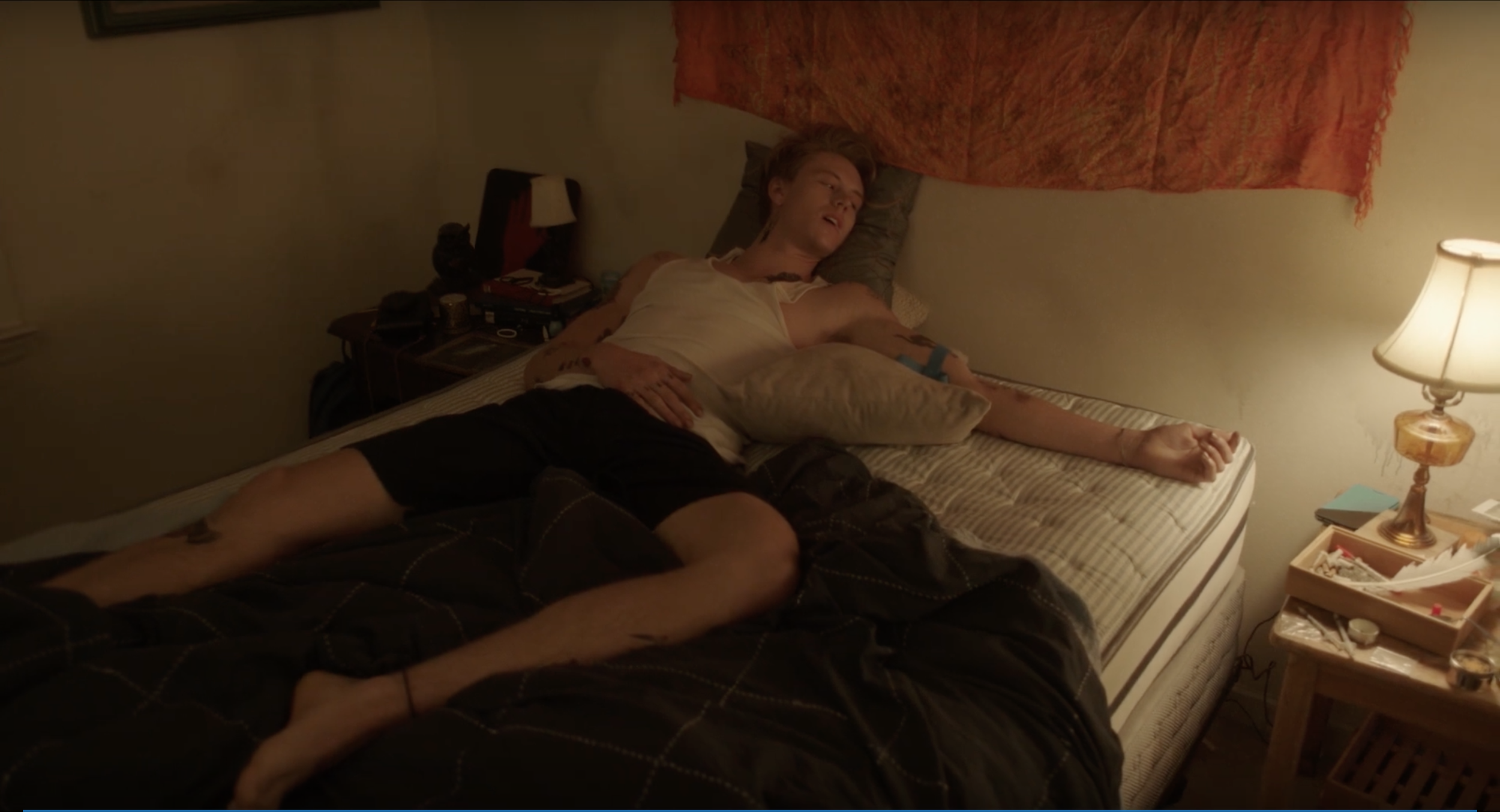Two people lying on a bed in a dim room.