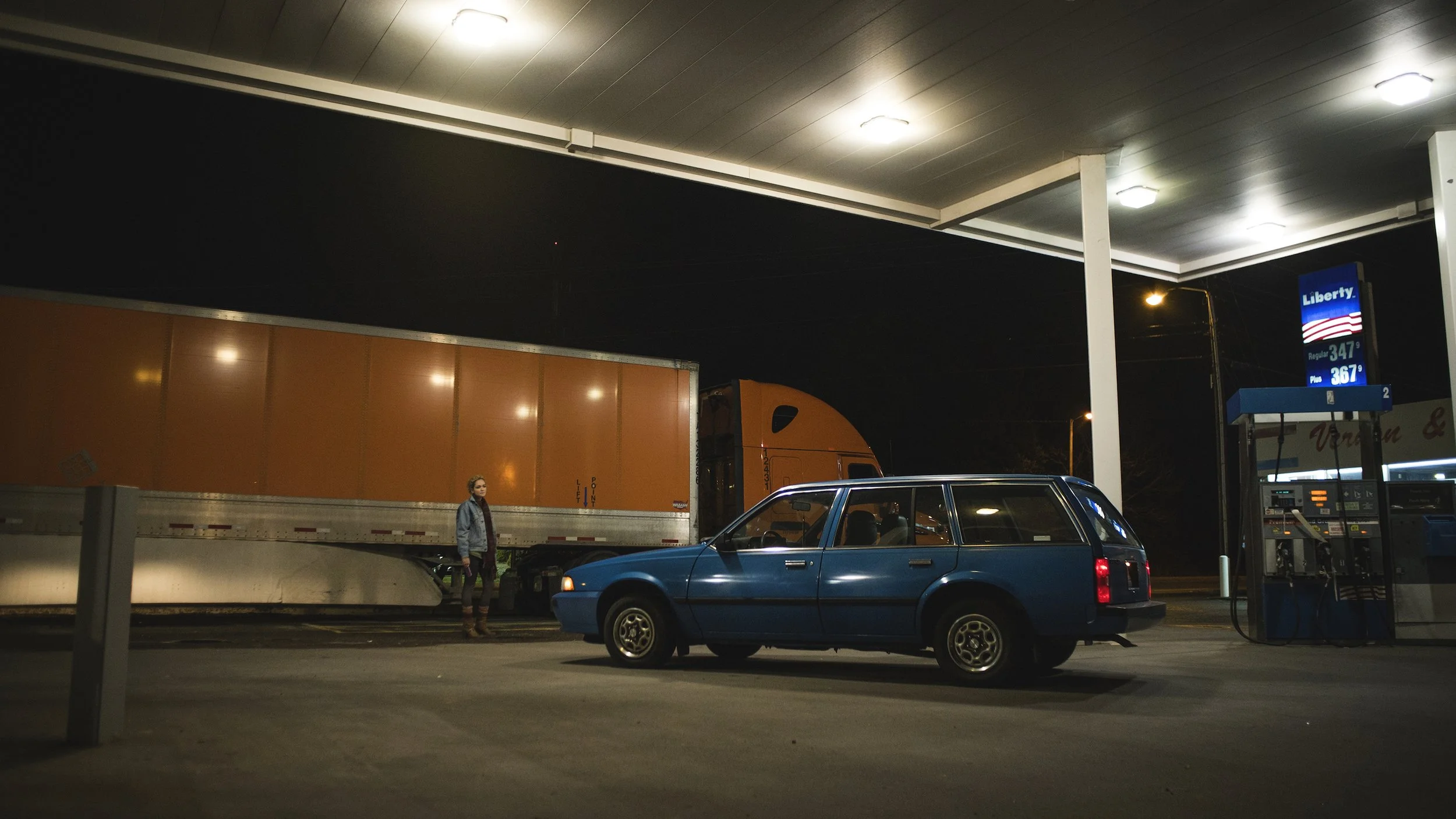 Night scene at a gas station with a blue car.