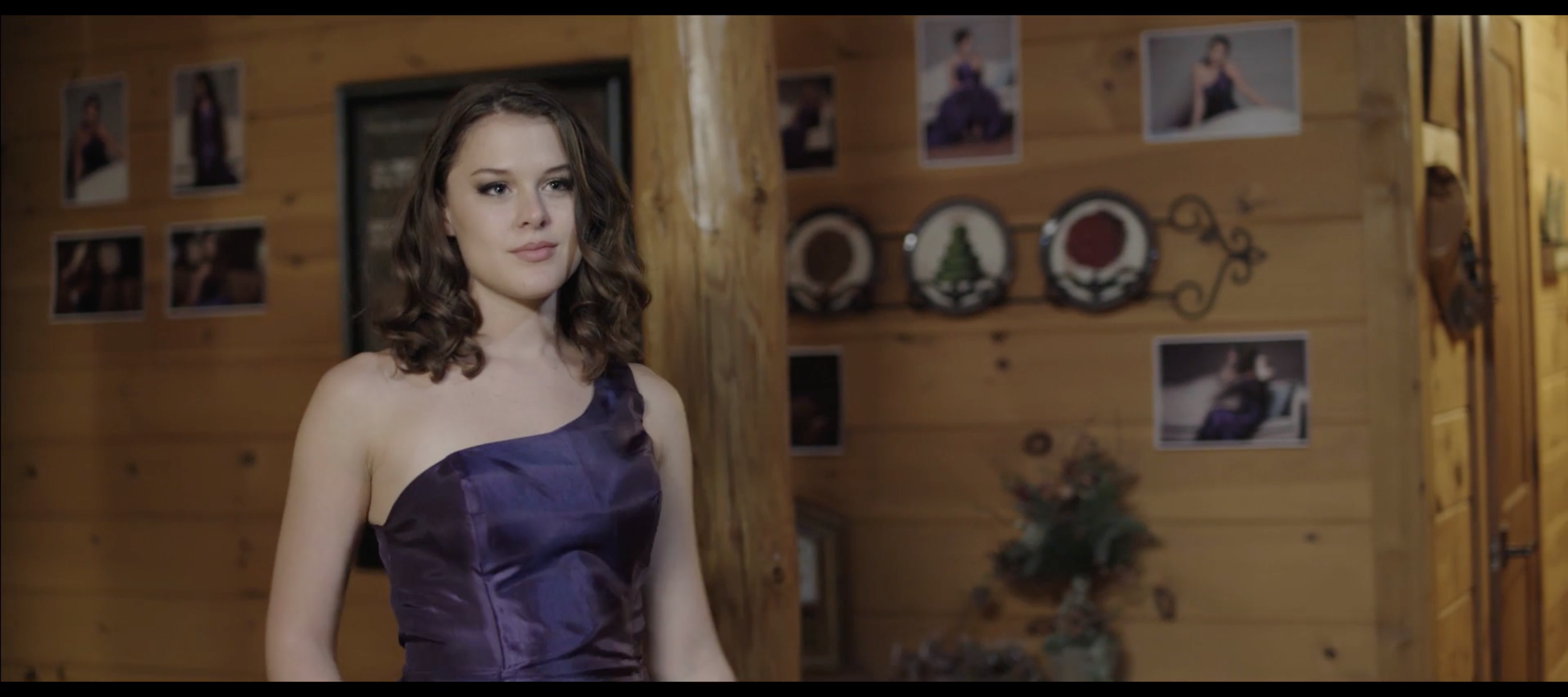 Woman in purple dress inside a cabin with photos.