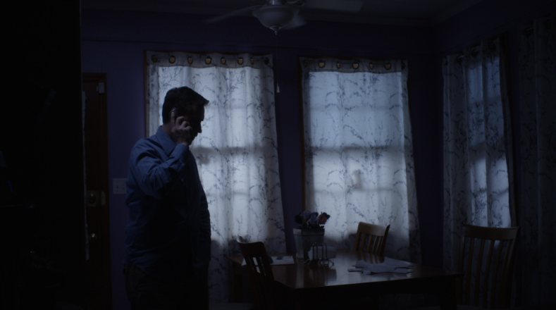 Man talking on phone in dimly lit room.