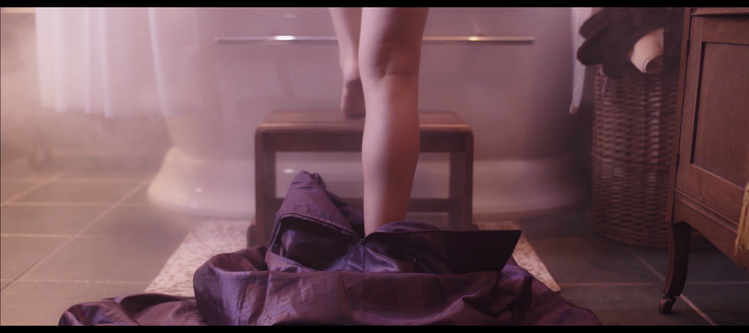 "Leg stepping over a coat in a misty room."