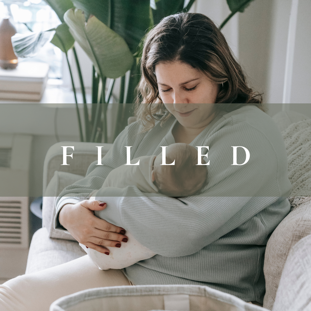A woman holding a newborn baby in her arms on a sofa in a living room.