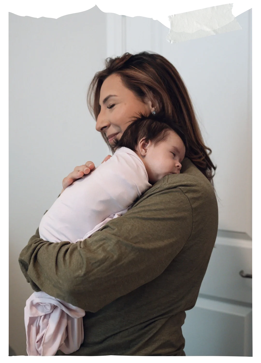 Woman gently holding and comforting a sleeping baby in her arms indoors, creating a calm and nurturing moment.