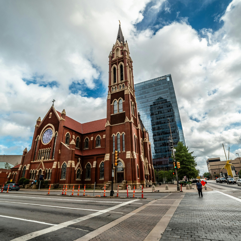 Historic church building in Dallas with modern city backdrop and street view