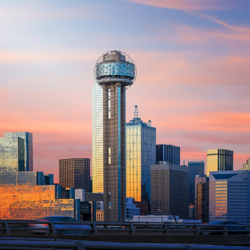 Reunion Tower rising above the downtown Dallas skyline at sunset, with modern skyscrapers reflecting warm evening light.