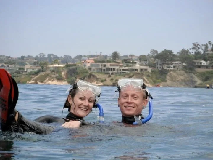 Two people smiling at La Jolla cove while on a San Diego Snorkel Tour