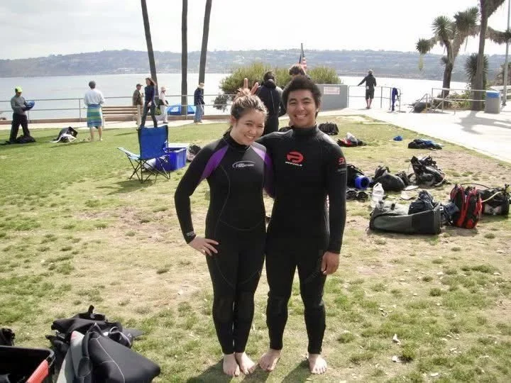 A group posing for the camera in their wetsuits before their snorkel tour in San Diego at La Jolla cove