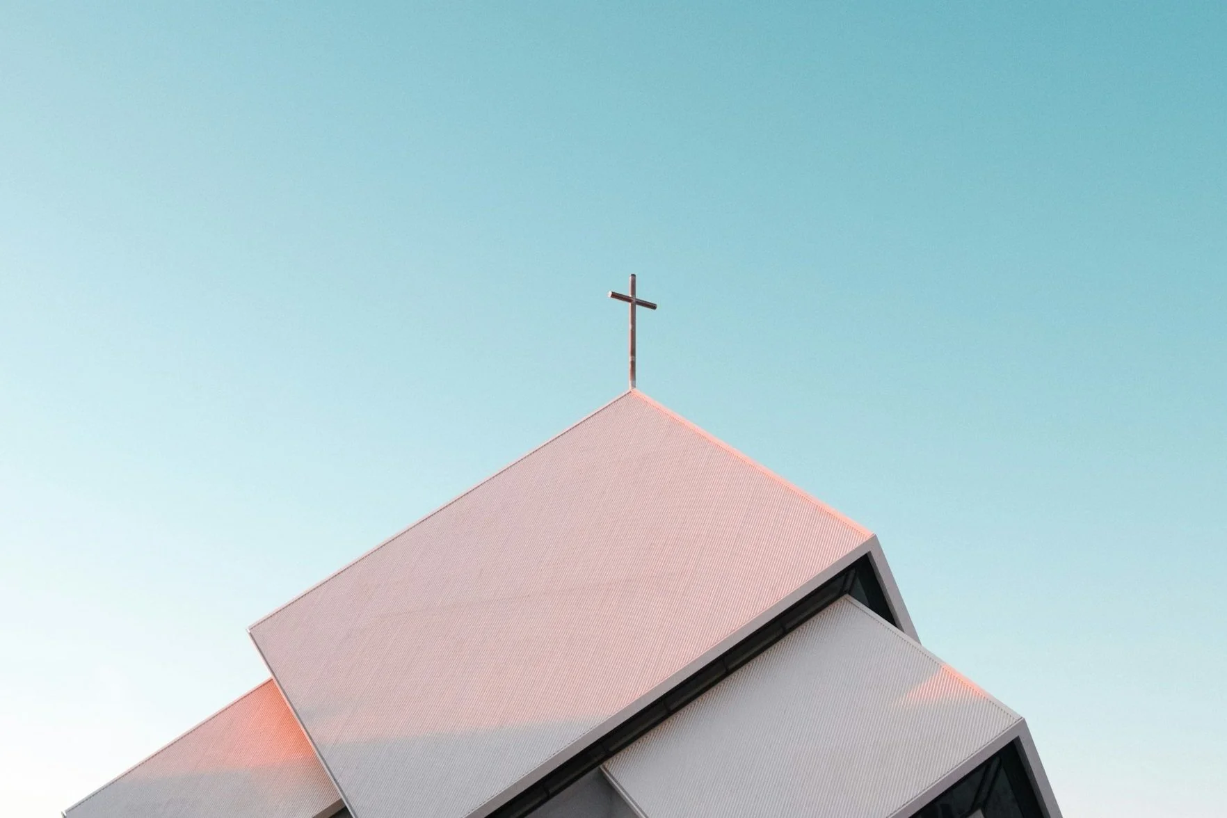 Modern church roof with cross against blue sky
