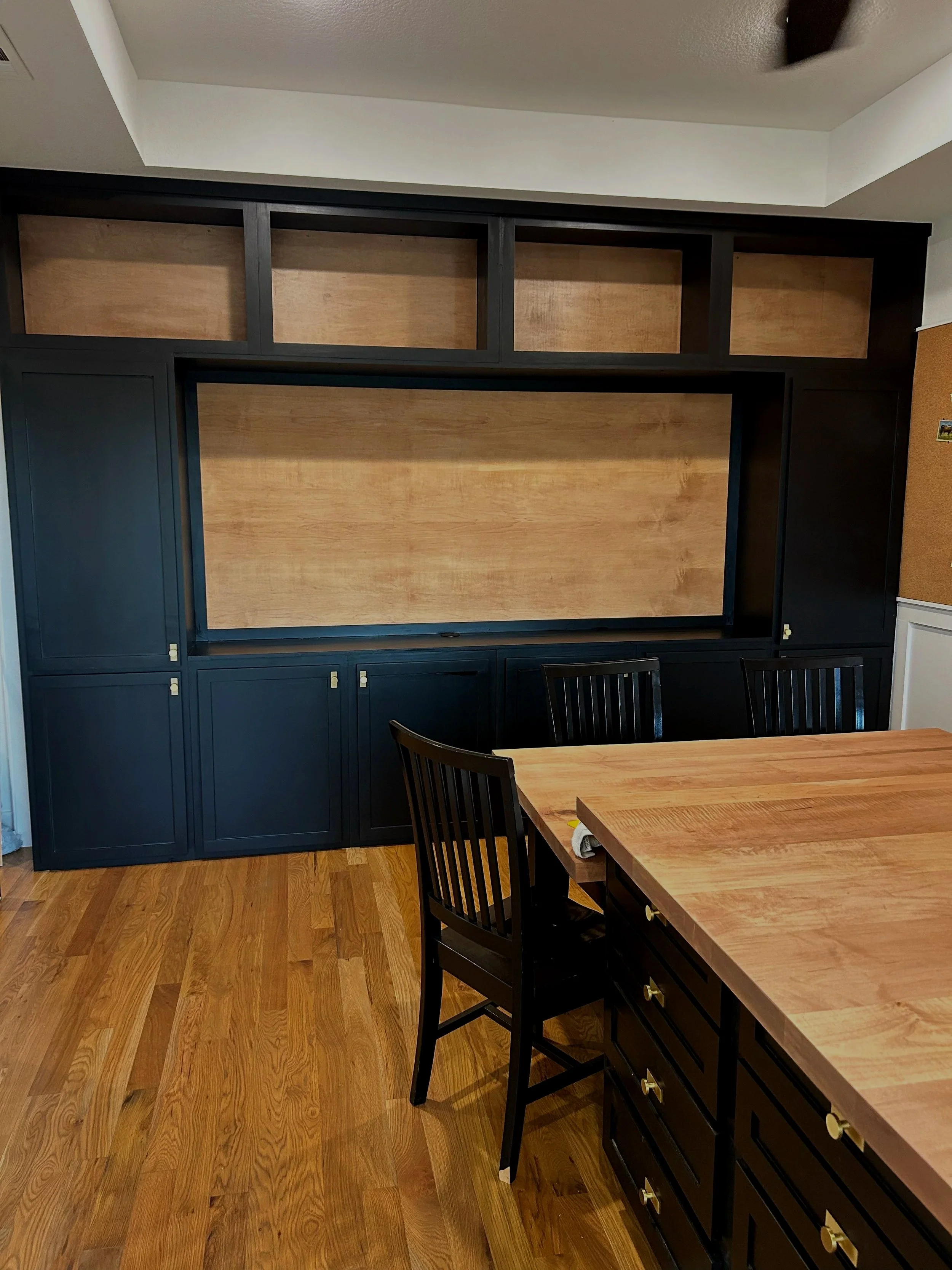 A large wooden entertainment center with black and natural wood finish in a craft room, family room, gameroom