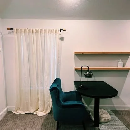 Built in black oval desk and floating shelves in a light wood color. small study nook. Small bedroom desk area with floating shelves