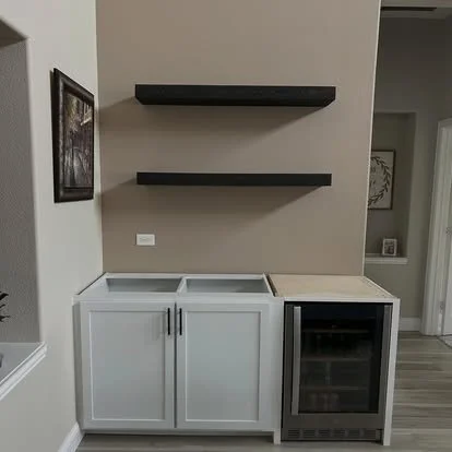 Custom bar built in with white cabinets made to fit the bar fridge and two floating cedar shelves above the bar
