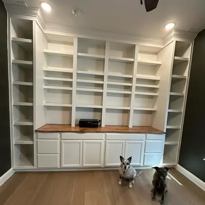 built in library with cabinets all painted white with a solid wood lived edge top stained light and with light wood. flooring. Custom solid wood built ins in dfw
