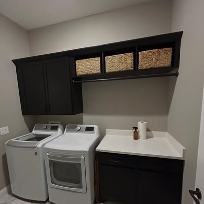 Black laundry room cabinets with wood basket storage and a hanging rod over a counter and more cabinets. 