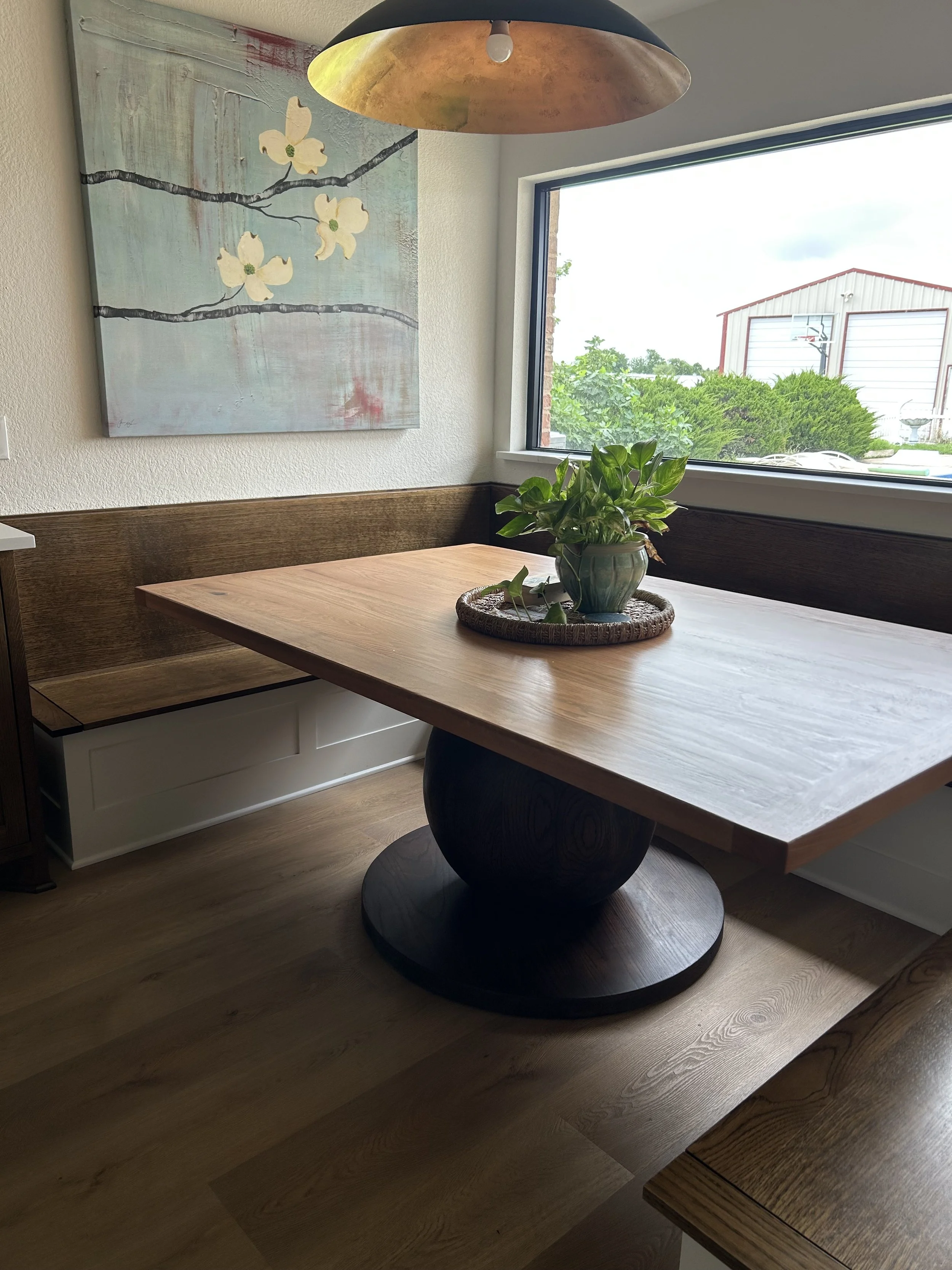 Solid wood table in a kitchen or breakfast nook the base is a solid wood ball and the table top is a solid oak table top it is all stained with a two tones organic stain.