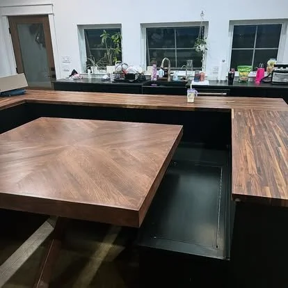 Solid cherry wood table top patterned with an x pattern and in a built in kitchen nook booth with walnut bar and booth table top.