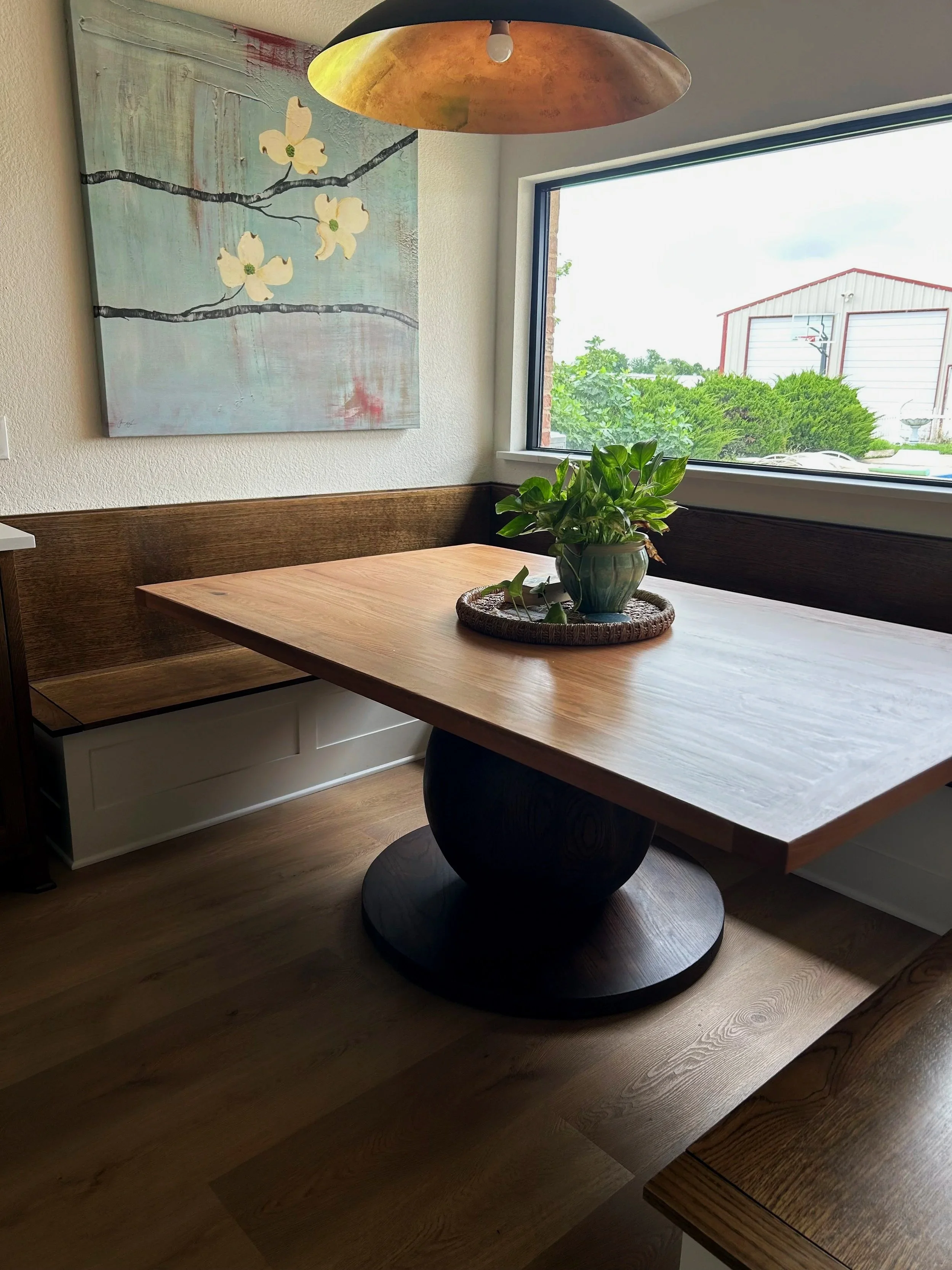 Unique solid wood custom table. the base has a solid oak ball and a two toned dark base with lighter table top. booth seating and table in the kitchen. solid oak table with built in booth