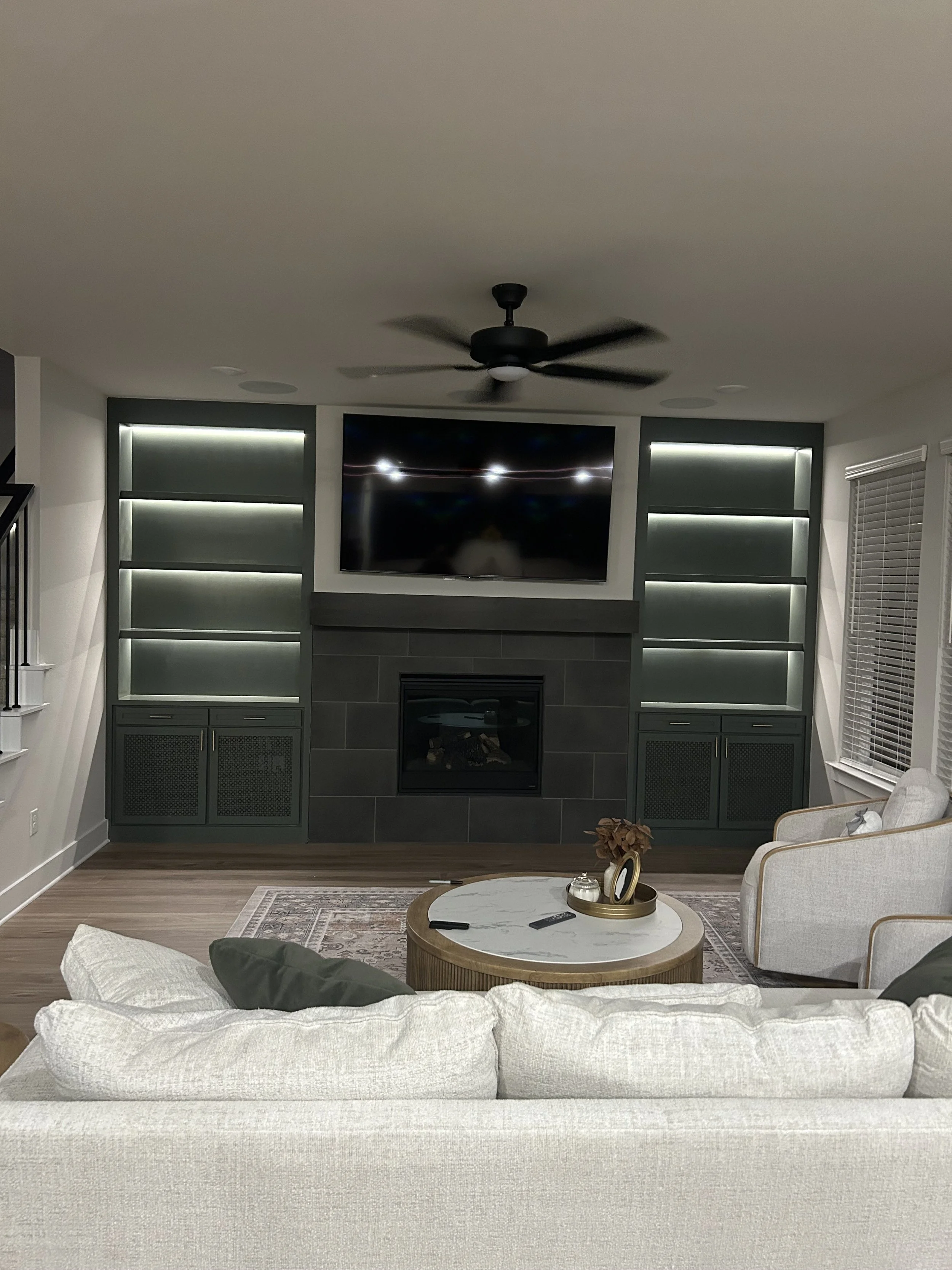 Living room / family room builtins on either sa\ide of the fire place. With bottom cabinets to home subs and audio equipment and then shelving that is lit up with inset lights. dimmable lighting in the built ins.