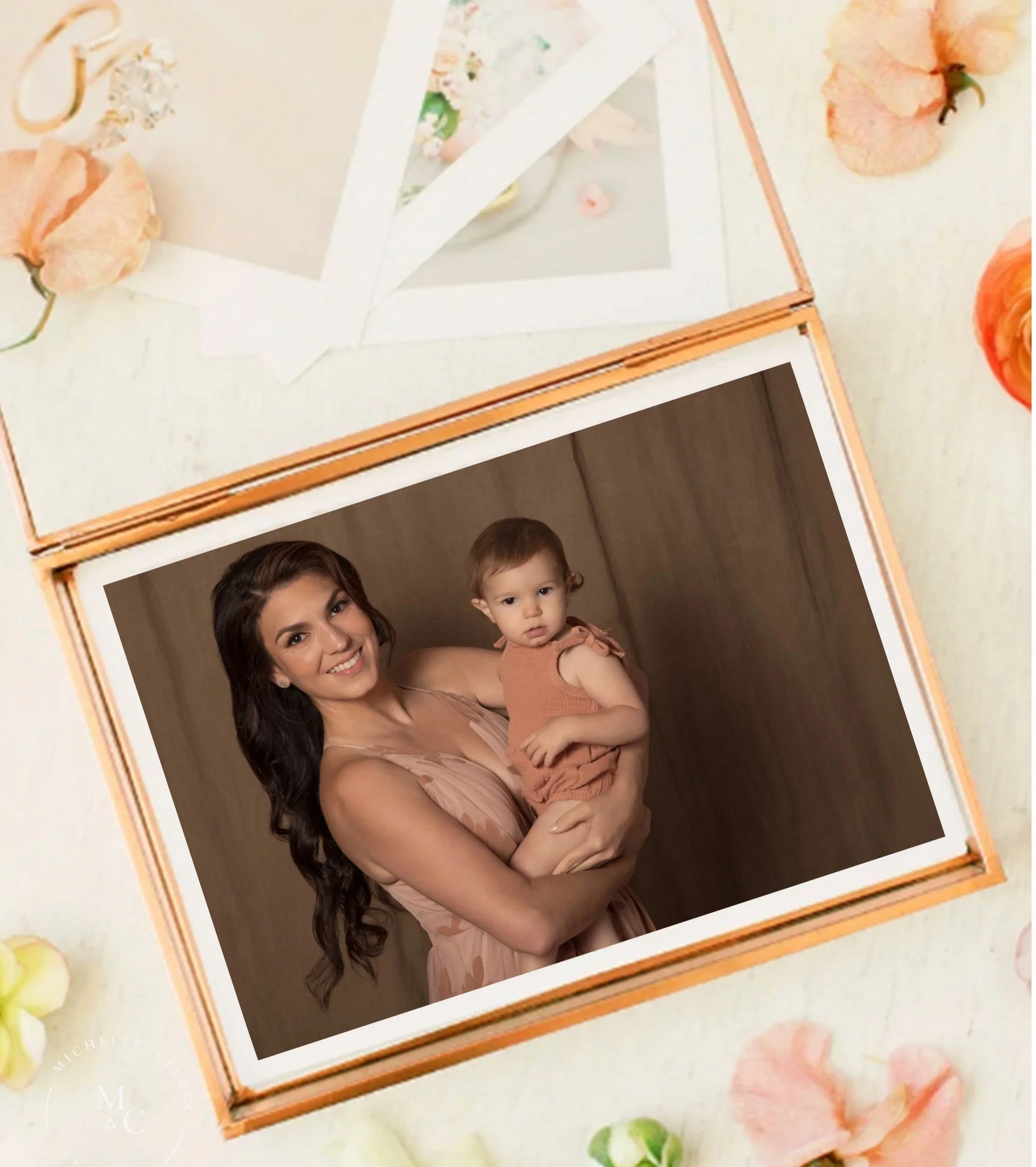 A woman holding a young girl in her arms, smiling at the camera, with a wooden background behind them.