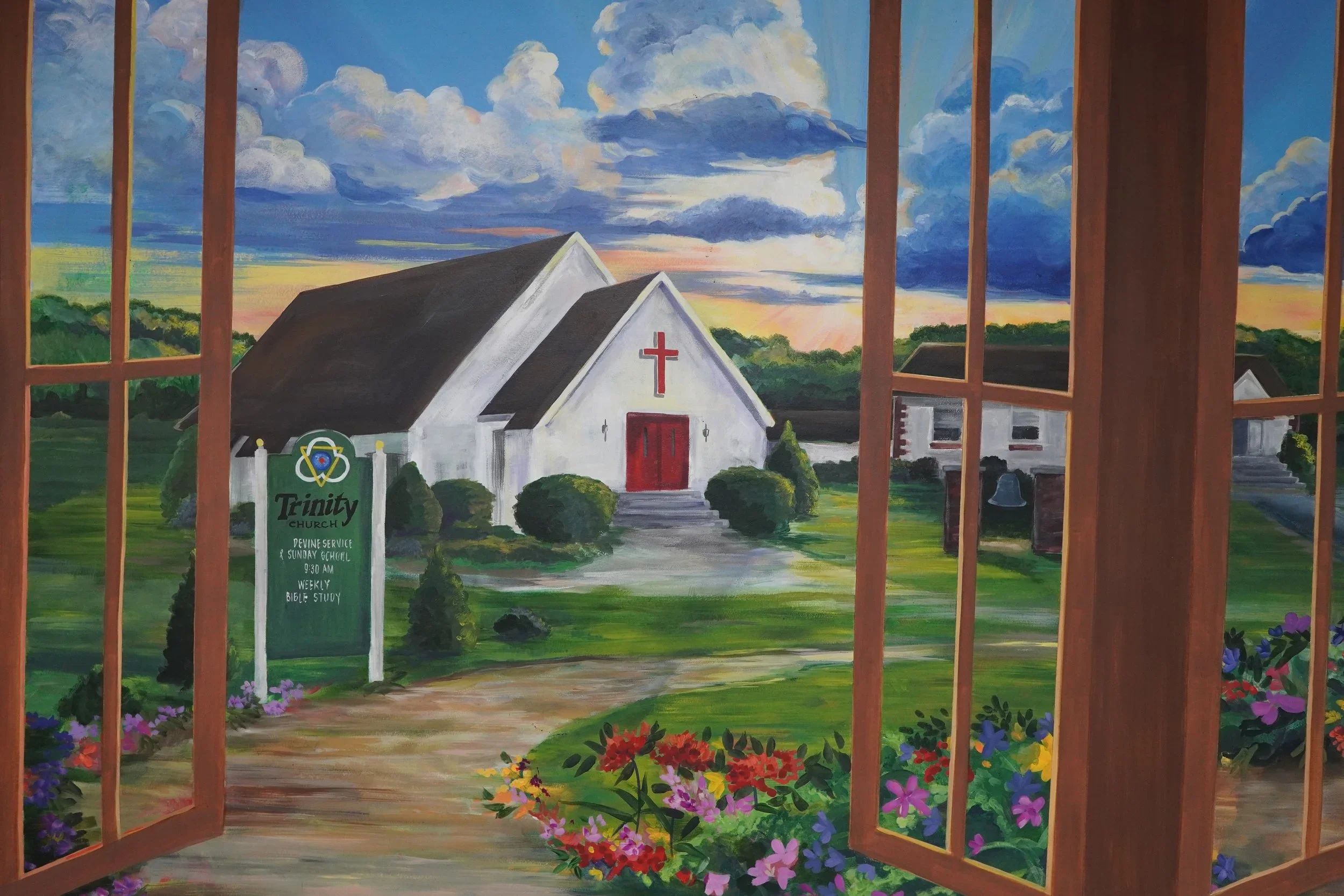 Painted view through open wooden doors of Trinity Church, featuring a white chapel with a red cross, church sign, flower gardens, fields, and dramatic clouds.