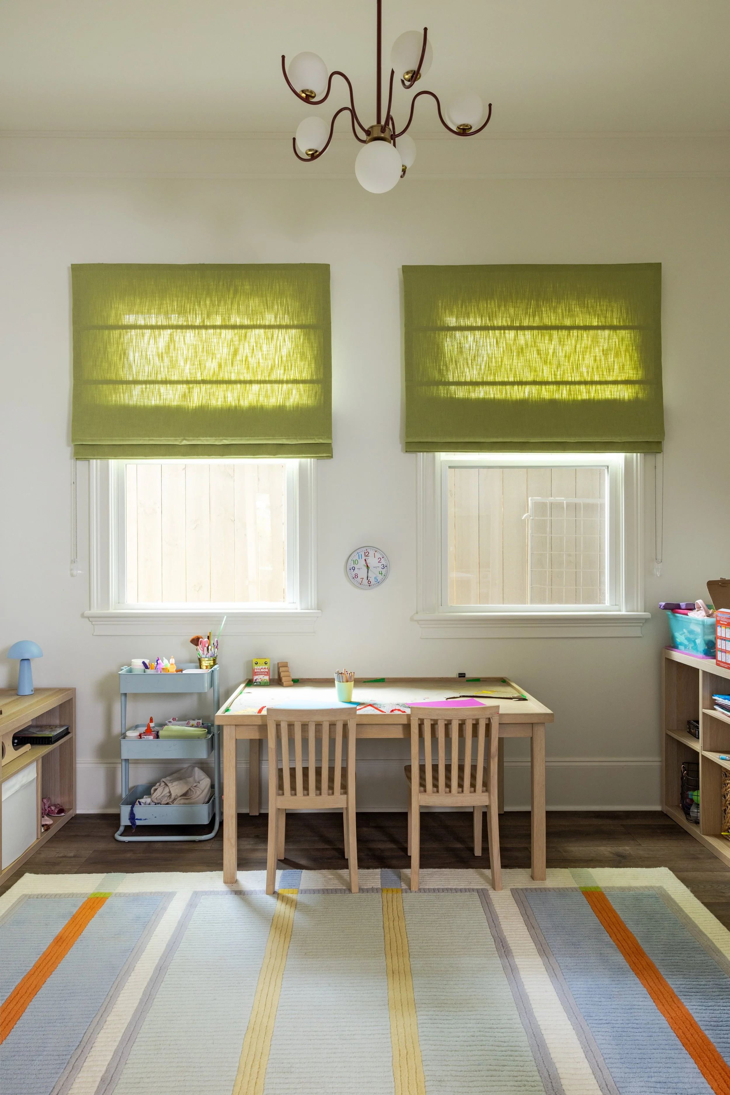 Playroom in a former side porch with green roman shades and squiggle chandelier