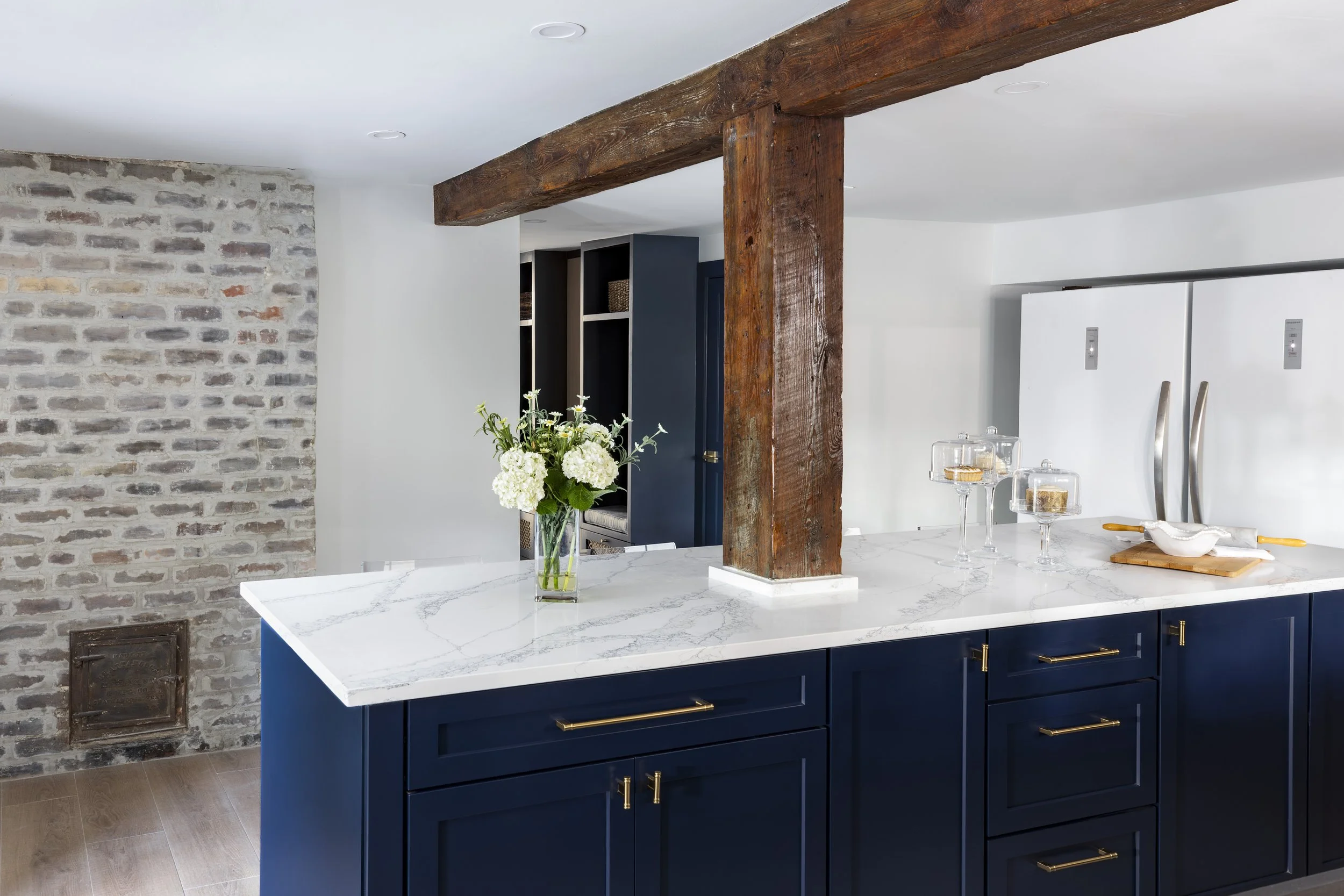Kitchen island with timber post, whitewashed brick, and old furnace door