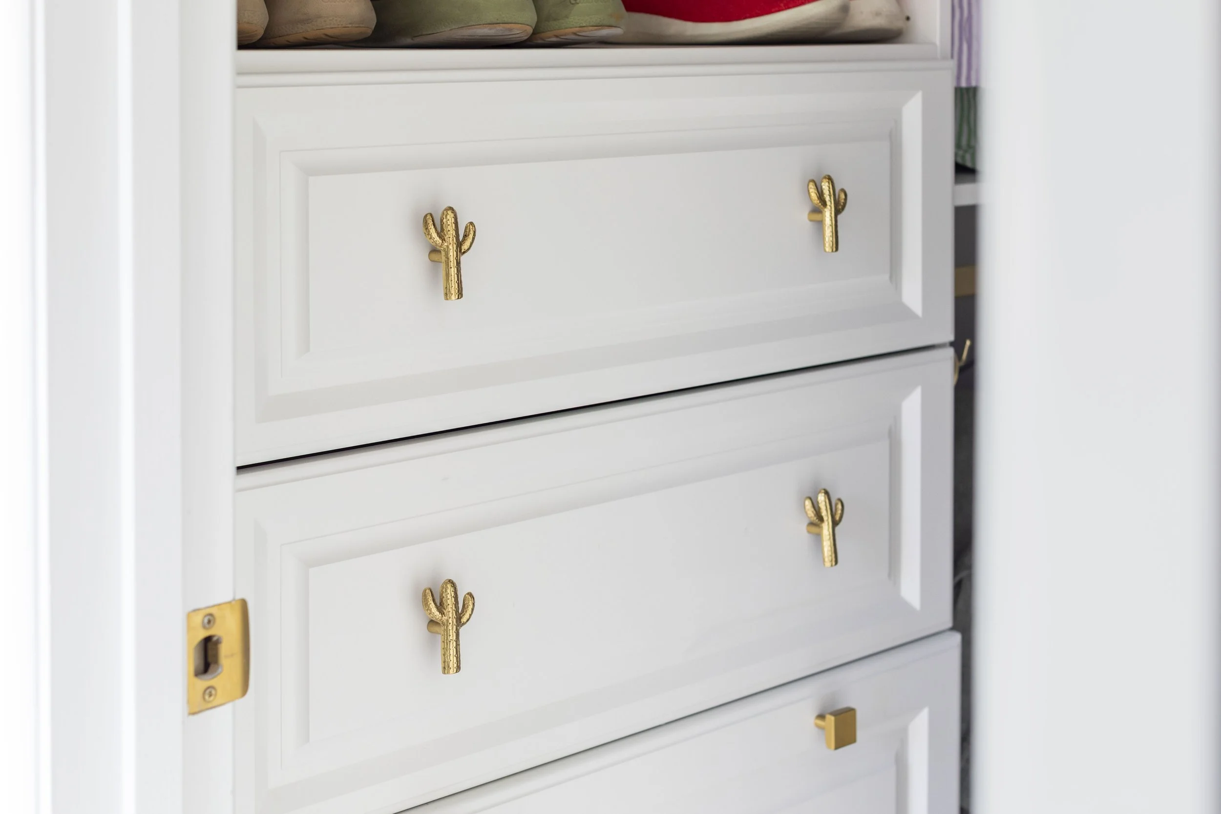 Brass cactus-shaped knobs on white closet drawers